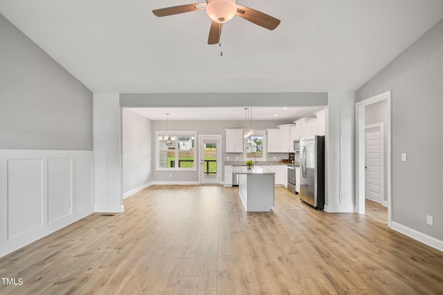 kitchen featuring pendant lighting, white cabinets, a kitchen island, stainless steel appliances, and light hardwood / wood-style flooring