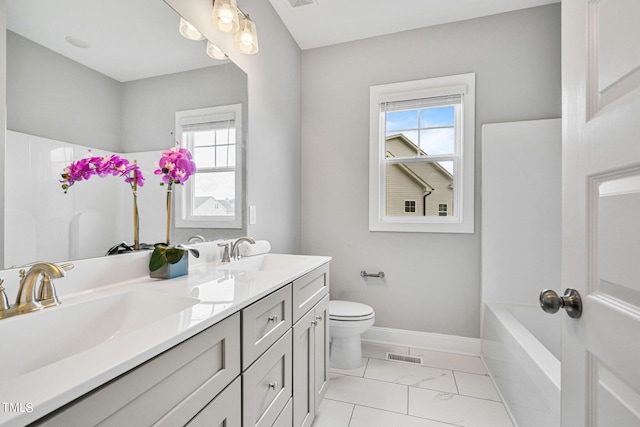 bathroom with vanity, toilet, and a healthy amount of sunlight