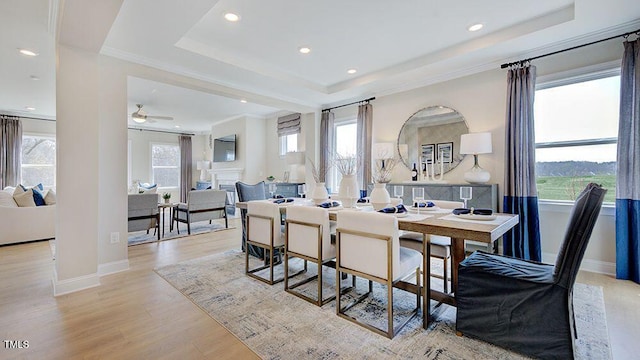 dining area featuring crown molding, light hardwood / wood-style flooring, and a raised ceiling