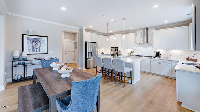 dining area featuring sink, ornamental molding, and light wood-type flooring