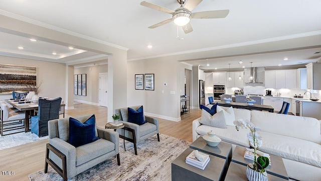 living room with ceiling fan, light wood-type flooring, and crown molding