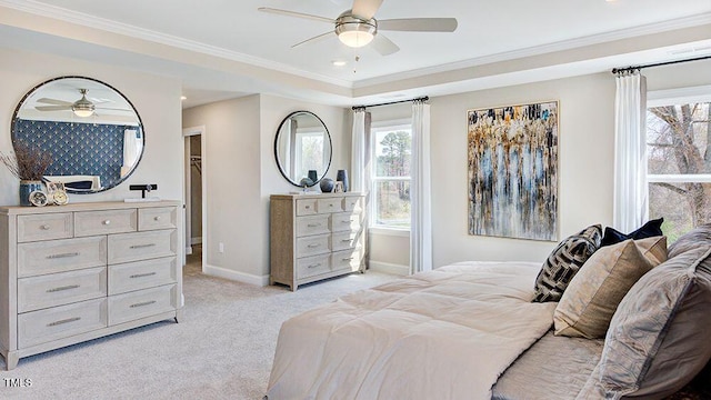 bedroom featuring ceiling fan, light carpet, a tray ceiling, and ornamental molding