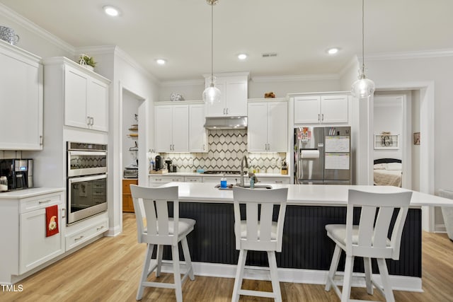 kitchen featuring white cabinets, a kitchen island with sink, hanging light fixtures, and stainless steel appliances