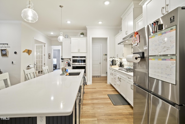 kitchen featuring pendant lighting, sink, white cabinetry, a center island with sink, and stainless steel appliances