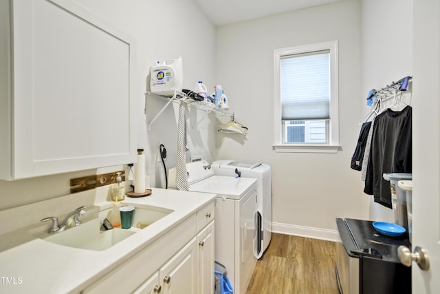 laundry room featuring washing machine and dryer, light wood-type flooring, cabinets, and sink