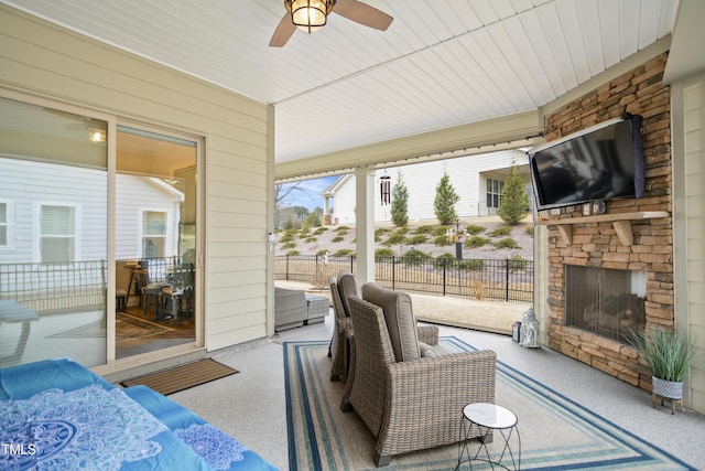 sunroom / solarium featuring ceiling fan and an outdoor stone fireplace