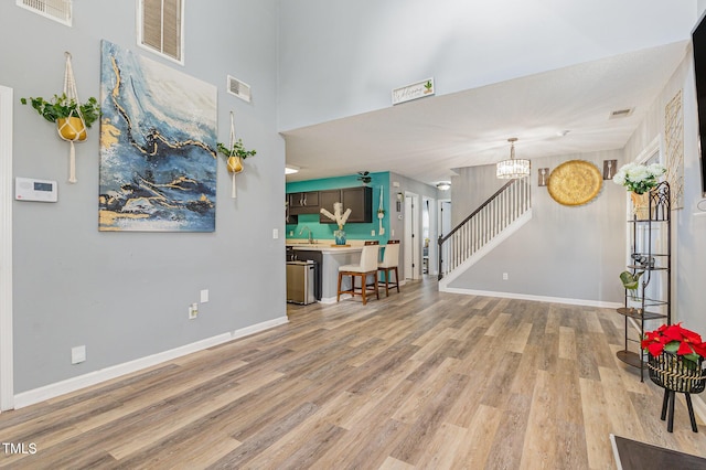 living room featuring light wood finished floors, stairway, visible vents, and baseboards