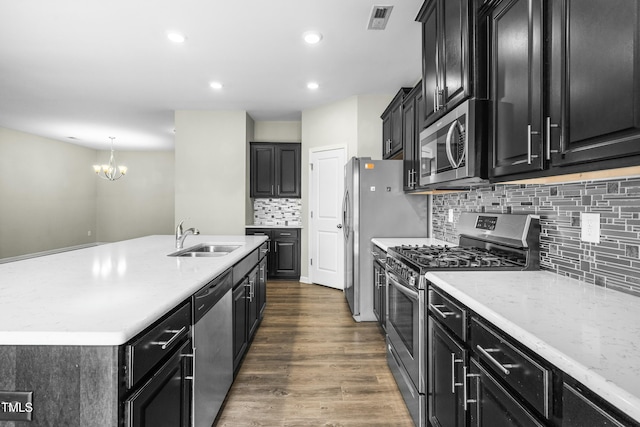 kitchen with appliances with stainless steel finishes, pendant lighting, tasteful backsplash, sink, and dark wood-type flooring