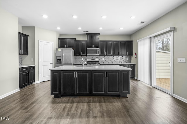 kitchen featuring an island with sink, appliances with stainless steel finishes, sink, and dark wood-type flooring