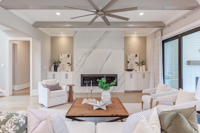 living room with beam ceiling, a premium fireplace, ceiling fan, and light wood-type flooring