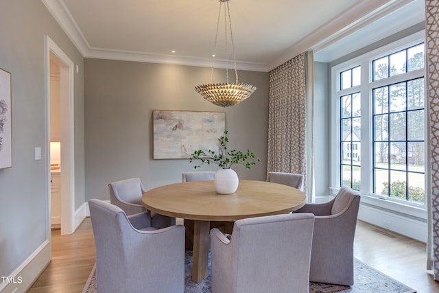 dining space featuring ornamental molding and light hardwood / wood-style floors