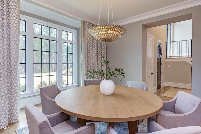 dining room with ornamental molding, a notable chandelier, and light wood-type flooring