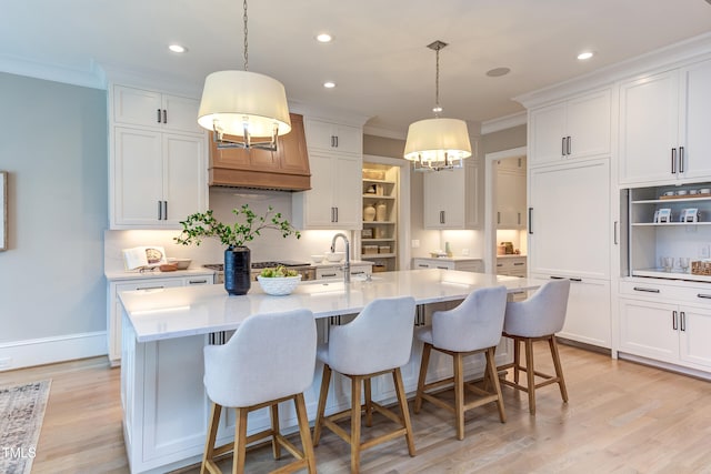 kitchen featuring white cabinetry, pendant lighting, and a center island with sink