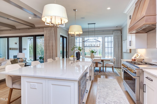 kitchen featuring premium range hood, an island with sink, white cabinets, and high end stove