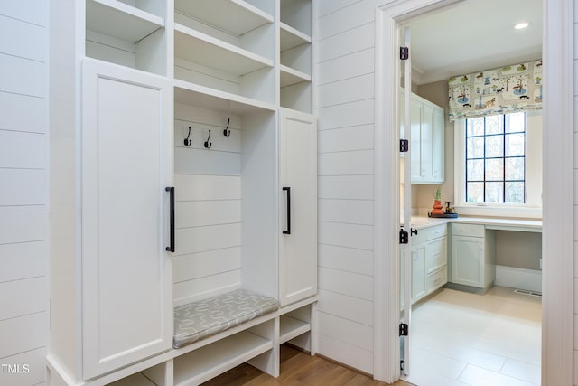 mudroom featuring built in desk and light wood-type flooring