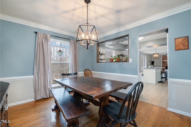 dining space with ornamental molding and light wood-type flooring