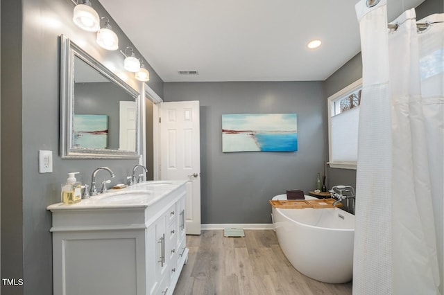 bathroom featuring hardwood / wood-style flooring, a tub to relax in, and vanity