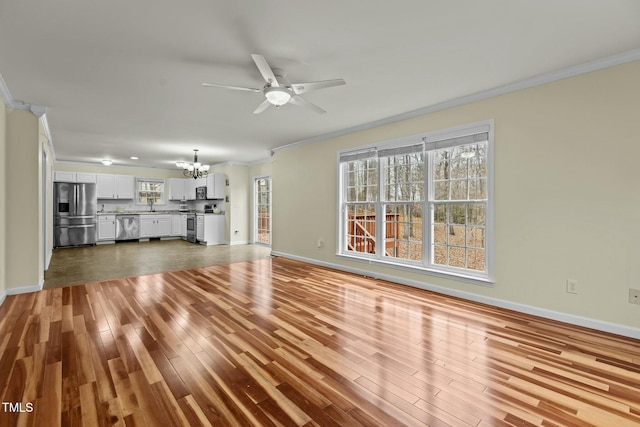 unfurnished living room with hardwood / wood-style floors, ceiling fan with notable chandelier, and ornamental molding