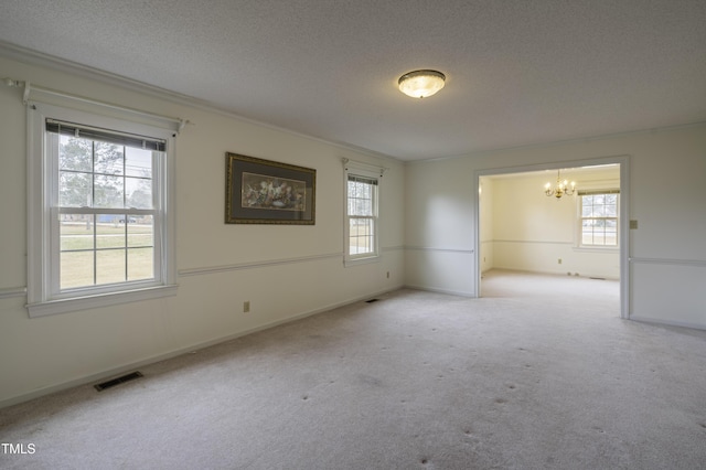 carpeted spare room with crown molding, a healthy amount of sunlight, a chandelier, and a textured ceiling