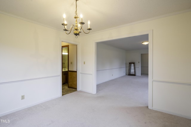 carpeted spare room with a notable chandelier and ornamental molding