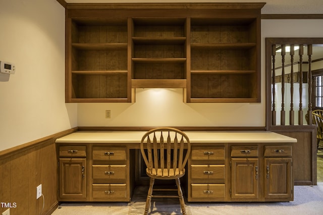 office area featuring light carpet, crown molding, built in desk, and wood walls