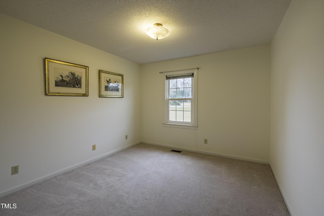 empty room featuring light colored carpet and a textured ceiling