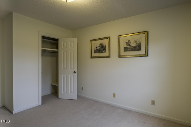 unfurnished bedroom featuring light colored carpet, a closet, and a textured ceiling