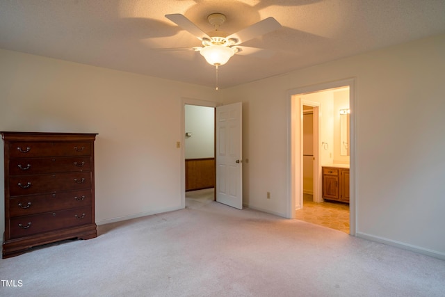 unfurnished bedroom with ceiling fan, ensuite bath, light carpet, and a textured ceiling