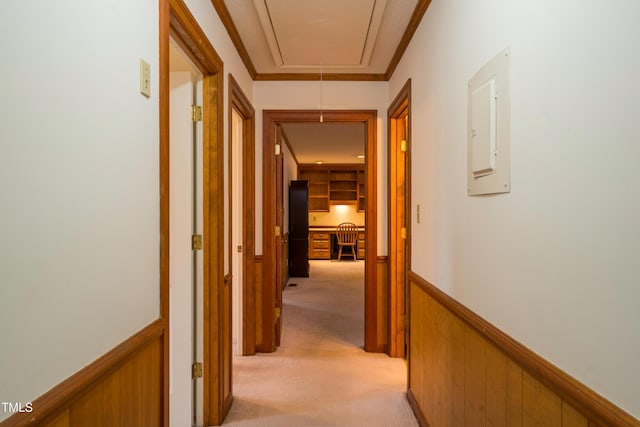 hallway with light colored carpet, ornamental molding, wooden walls, and electric panel