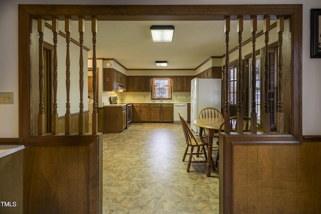 kitchen featuring crown molding, sink, white appliances, and wood walls