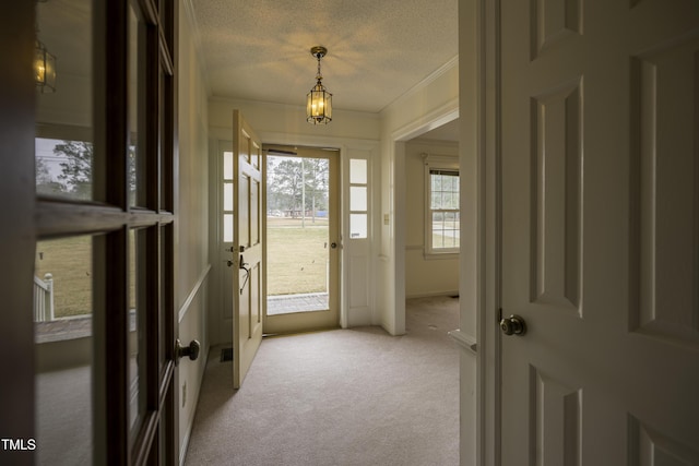 doorway to outside featuring ornamental molding, light colored carpet, and a textured ceiling