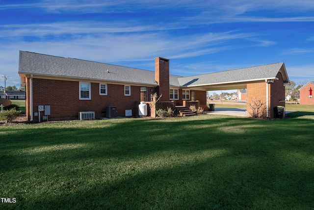 rear view of house featuring a carport, cooling unit, and a lawn