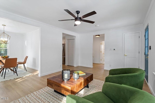 living room featuring crown molding, ceiling fan with notable chandelier, and light hardwood / wood-style floors