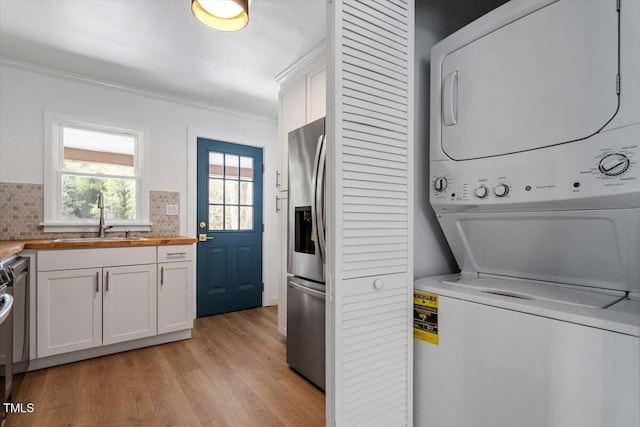 washroom featuring stacked washer and dryer, crown molding, light hardwood / wood-style floors, and sink