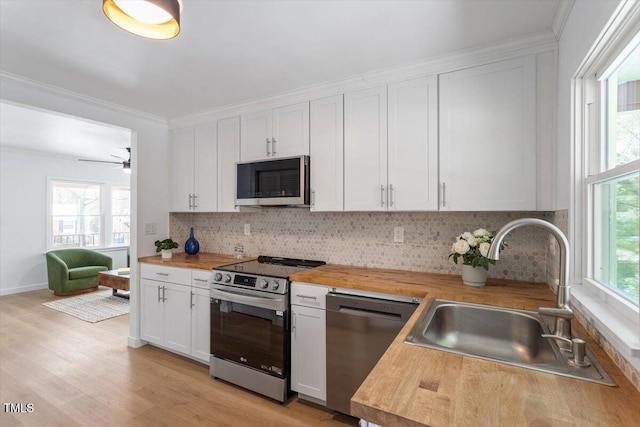 kitchen featuring wood counters, sink, white cabinetry, a wealth of natural light, and stainless steel appliances