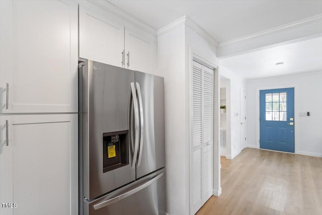 kitchen with white cabinets, crown molding, stainless steel fridge, and light hardwood / wood-style floors