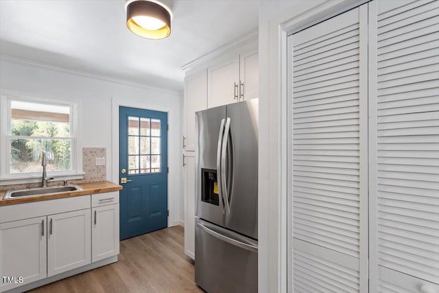 kitchen with white cabinetry, stainless steel fridge with ice dispenser, sink, and butcher block counters