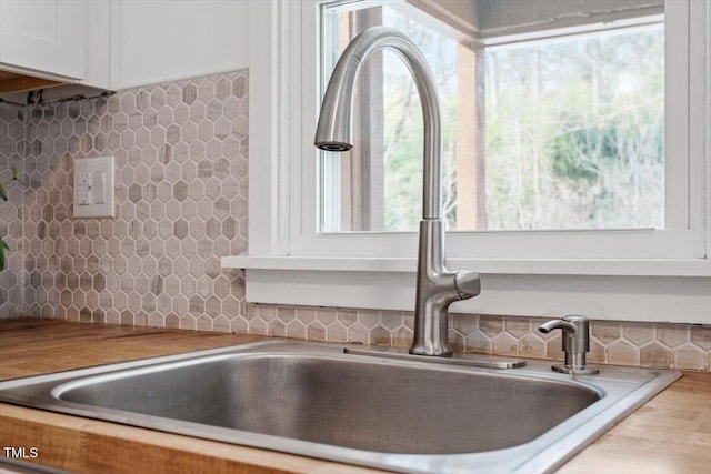 room details featuring backsplash, sink, and white cabinets