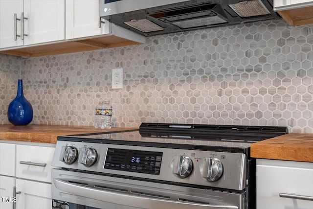 interior space with stainless steel electric stove, wood counters, range hood, white cabinets, and decorative backsplash