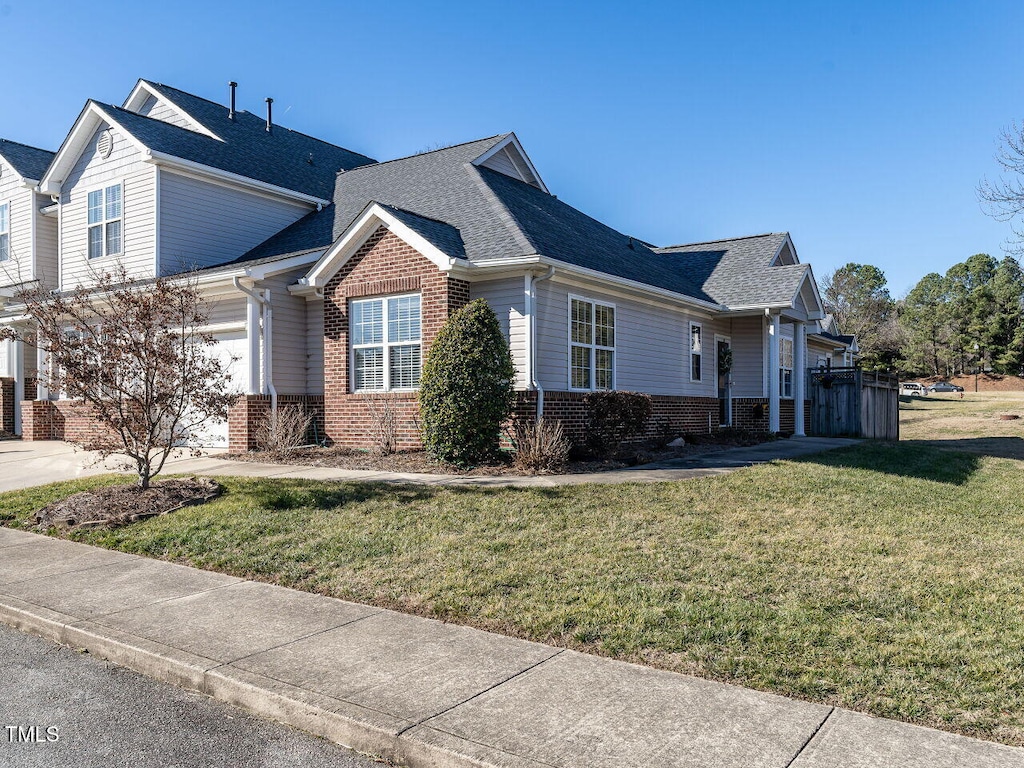 view of property exterior featuring driveway, brick siding, a lawn, and a shingled roof