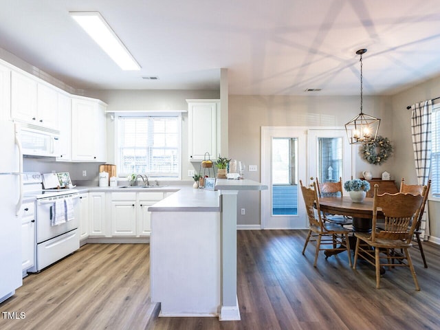 kitchen featuring white appliances, a sink, white cabinets, light countertops, and pendant lighting