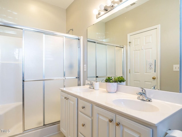 bathroom with double vanity, an enclosed shower, visible vents, and a sink