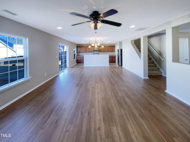 unfurnished living room with ceiling fan with notable chandelier and dark hardwood / wood-style floors