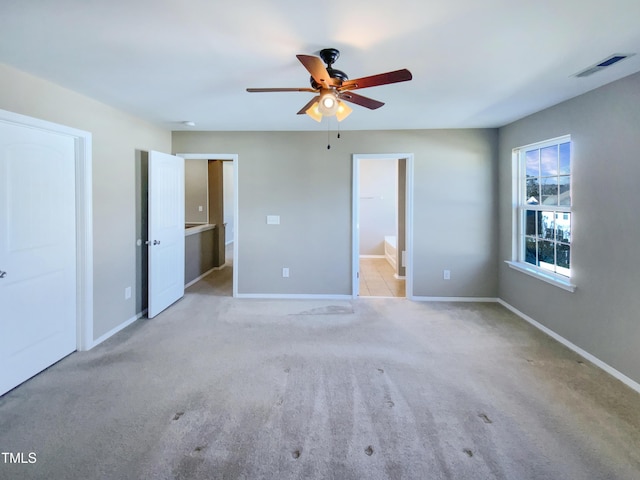 unfurnished bedroom featuring ceiling fan, ensuite bathroom, and light carpet