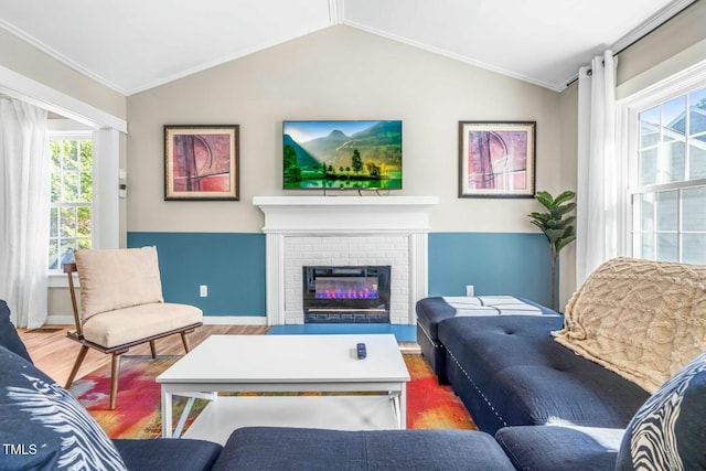 living room with vaulted ceiling, a brick fireplace, crown molding, and hardwood / wood-style floors