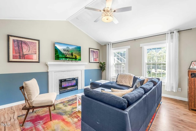 living room featuring a brick fireplace, hardwood / wood-style floors, ceiling fan, and vaulted ceiling