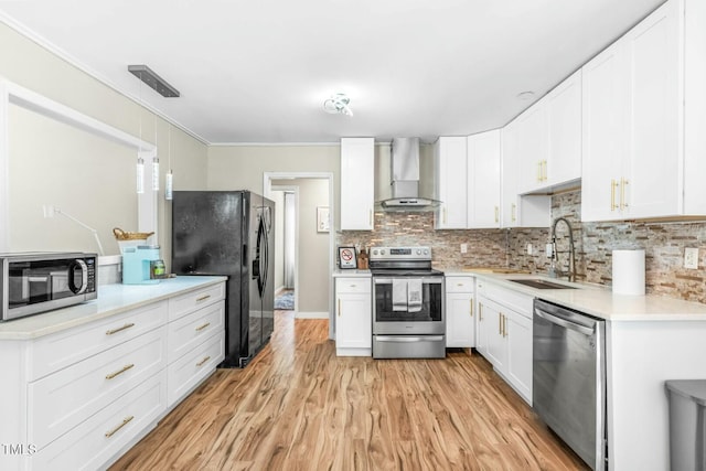 kitchen with pendant lighting, white cabinets, appliances with stainless steel finishes, wall chimney exhaust hood, and sink