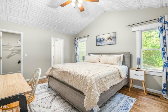 bedroom featuring light hardwood / wood-style floors, multiple windows, ceiling fan, and a spacious closet