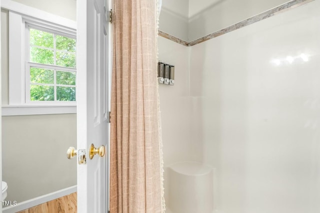 bathroom with hardwood / wood-style flooring, a wealth of natural light, and a shower with curtain