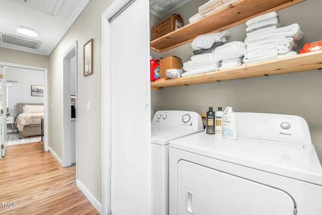 laundry area with washer and clothes dryer, ornamental molding, and light wood-type flooring